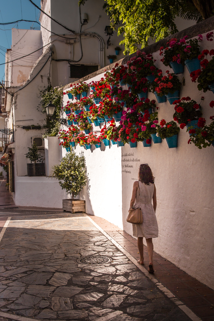 a woman walking next to a walk decorated with flower pots in Marbella, Southern Spain