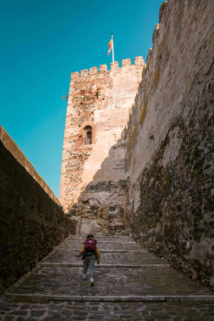 a boy walking up to the entrance gate of Fuengirola castle in summer