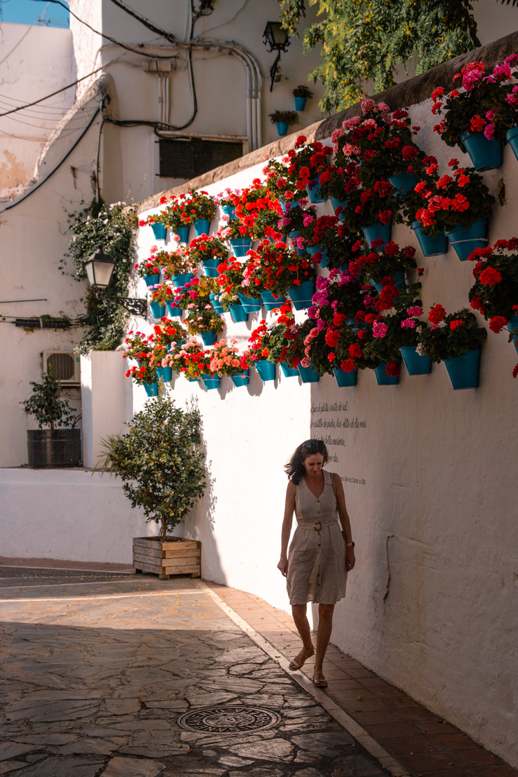 a woman posing next to flower pots on walls in Marbella old town, Southern Spain